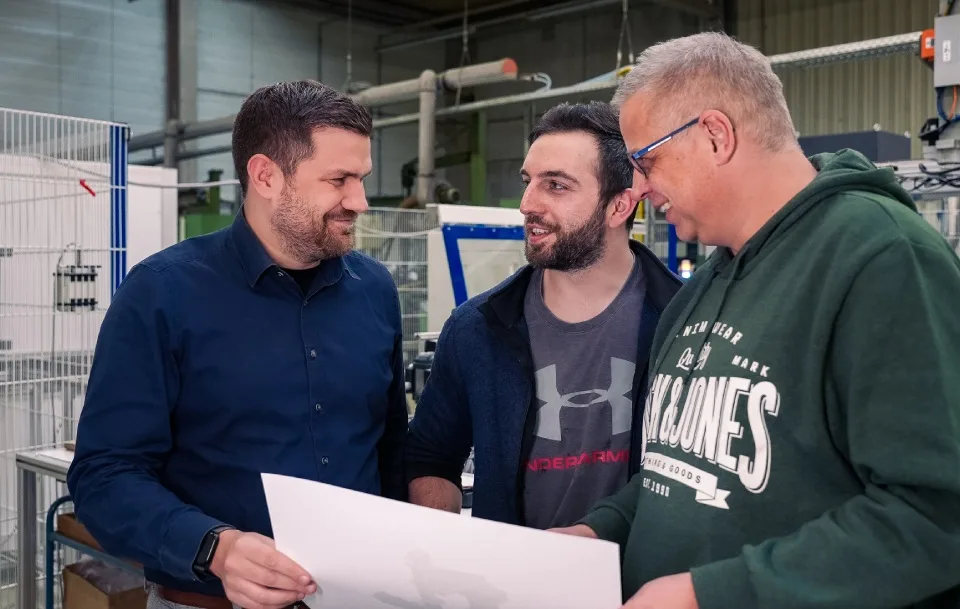 Baumgarten-Mitarbeiter besprechen Fertigungsunterlagen in der Produktionshalle in Burbach