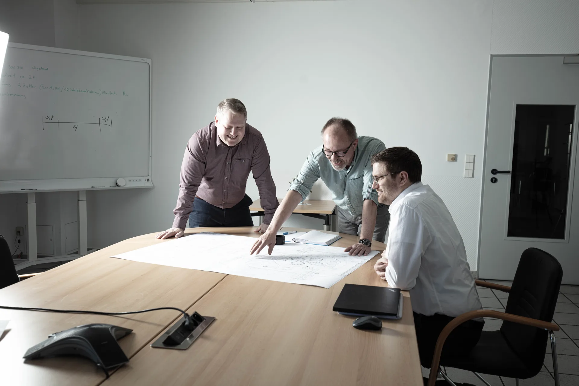 Konstruktionsteam bespricht eine technische Zeichnung am Whiteboard