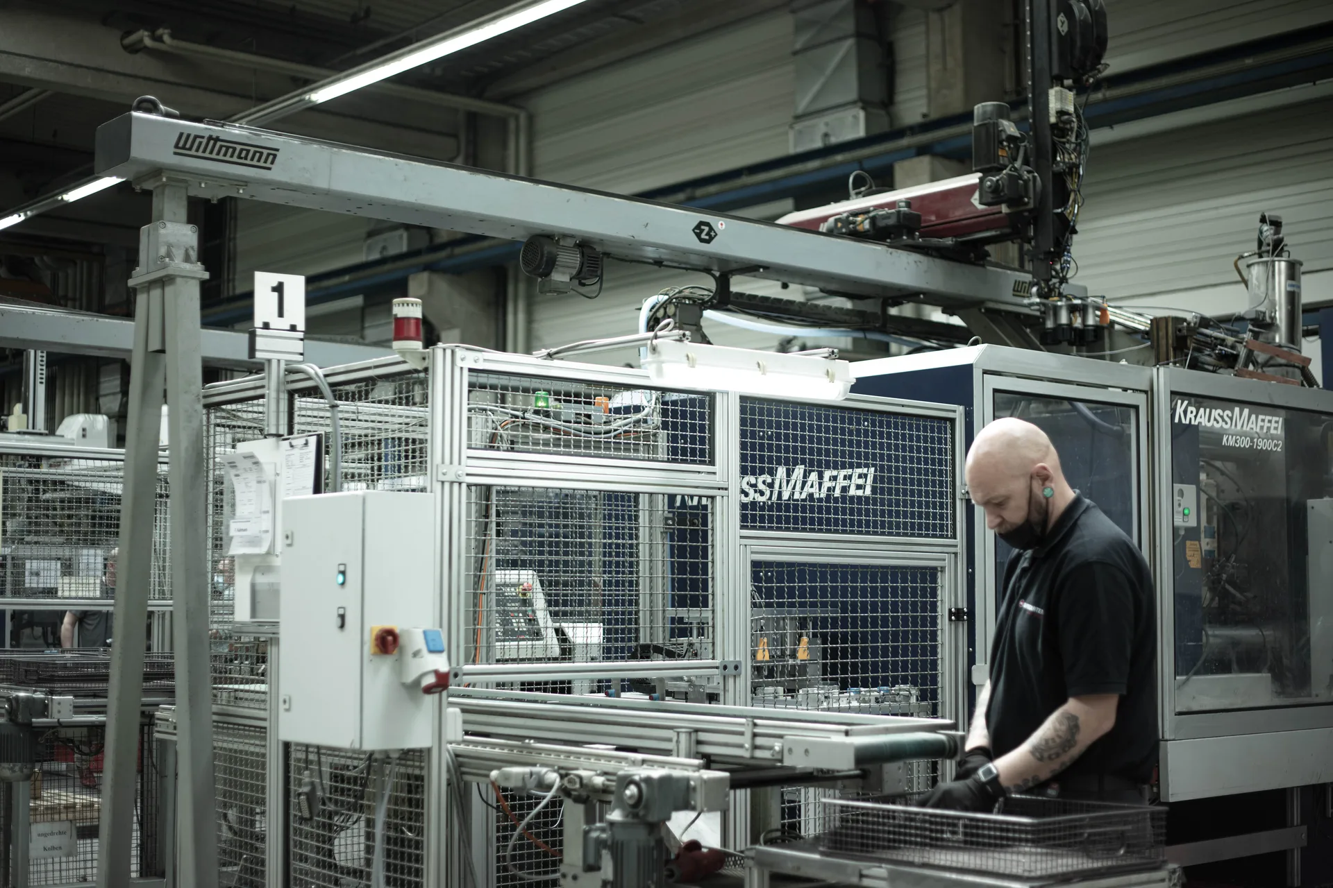 Werker an einer KraussMaffei-Duroplast-Spritzgießmaschine mit Wittmann-Greifer